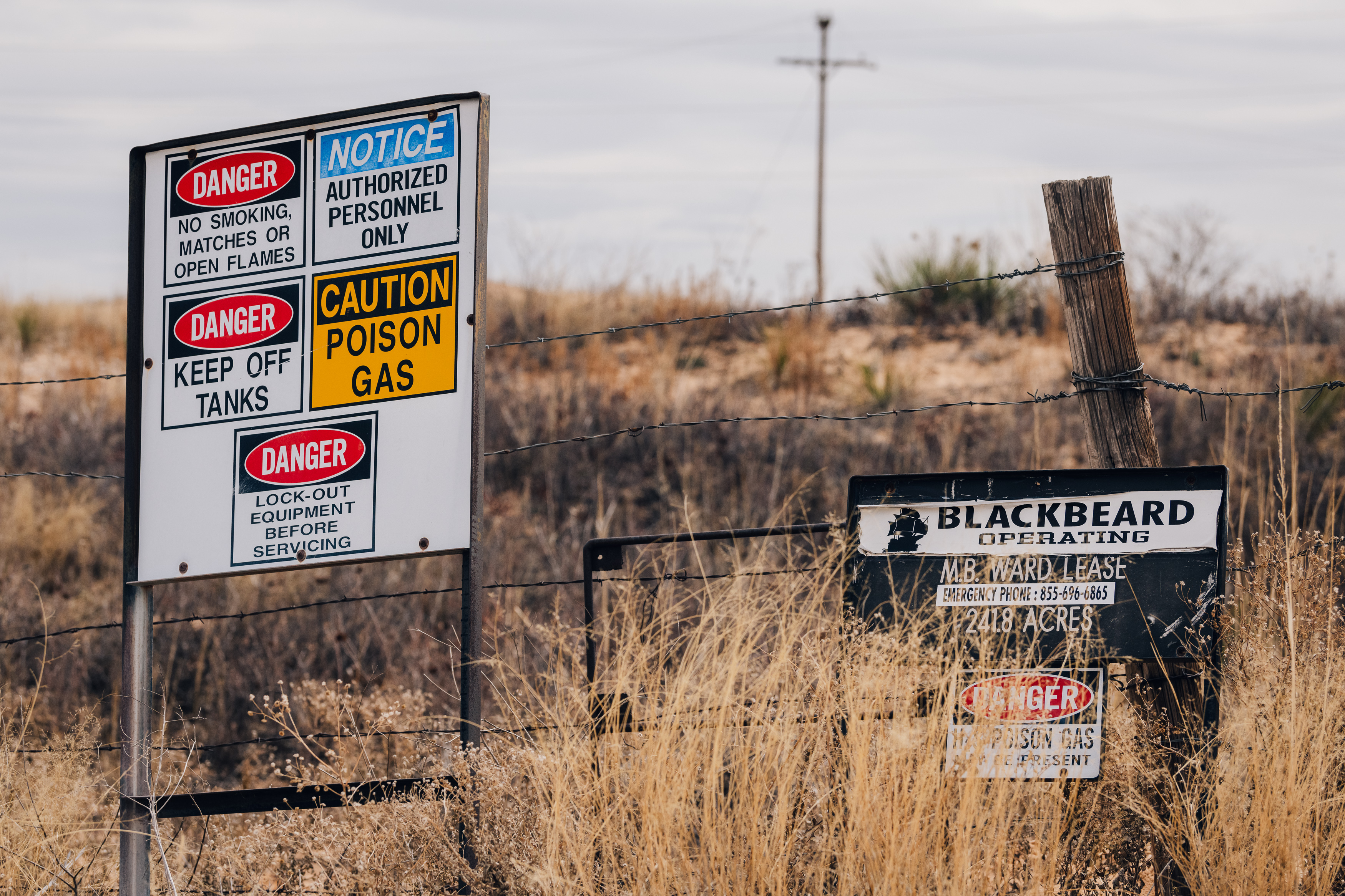 Danger signs about poison gas and flammability risks at an oil and gas site in the Permian