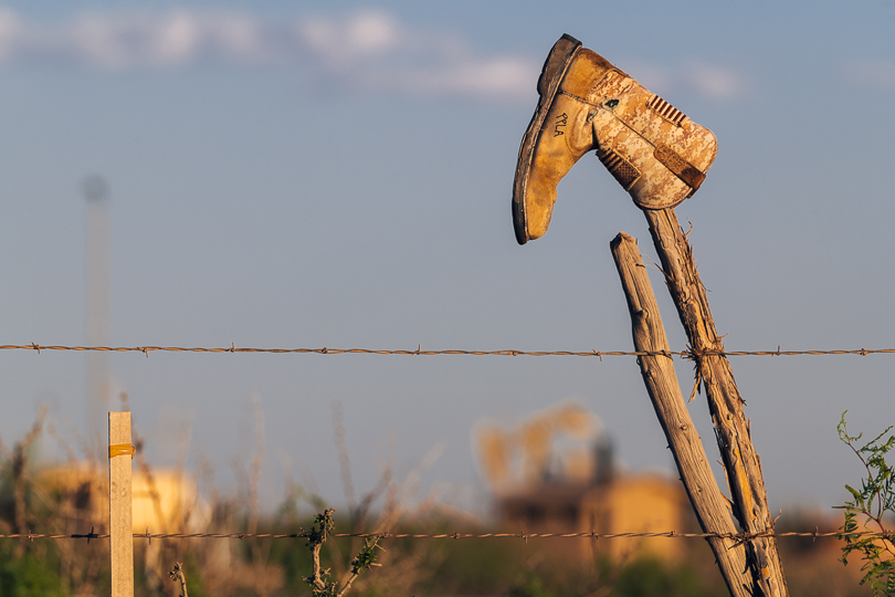 Laid off workers hang their boots on fence posts in the Permian Basin Shale in spring 2020