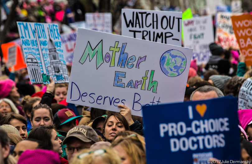 A woman marcher holds a sign reading 'Mother Earth deserves better.'