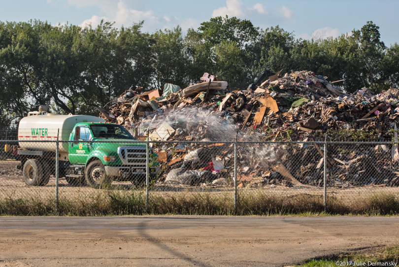 Truck spraying water to keep down the dust at a storm debris dump