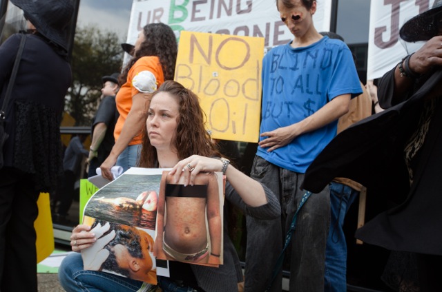 Kindra Arnesen holds photos of people and animals sickened by the BP oil spill.