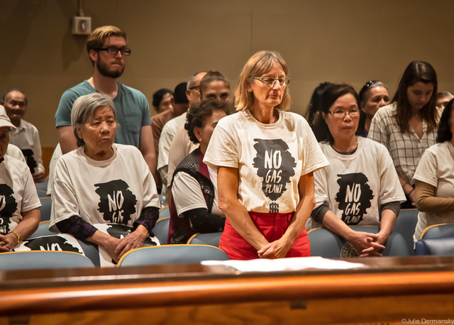 Renate Heurich stands while Vietnamese community members from New Orleans East pray