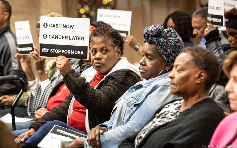 Opponents hold signs protesting Formosa's proposed petrochemical plant at a St. James Parish Council meeting