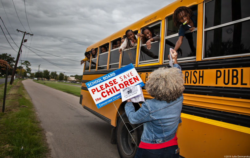 Lydia Gerard hands kids on a school bus information about pollution concerns