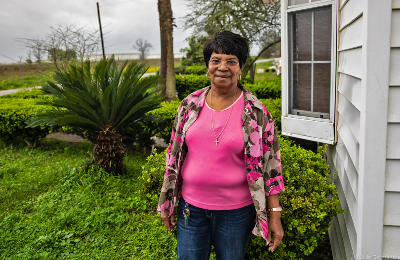 Geraldine Mayho in front of her home on Burton Street across from oil storage tanks in St. James, Louisiana