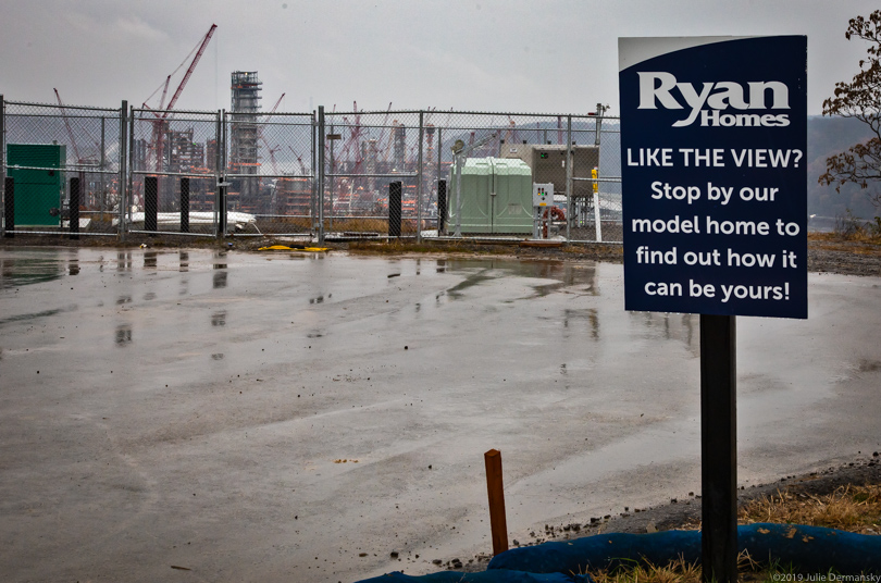 Housing development sign about liking the view, which shows Shell's petrochemical complex under construction