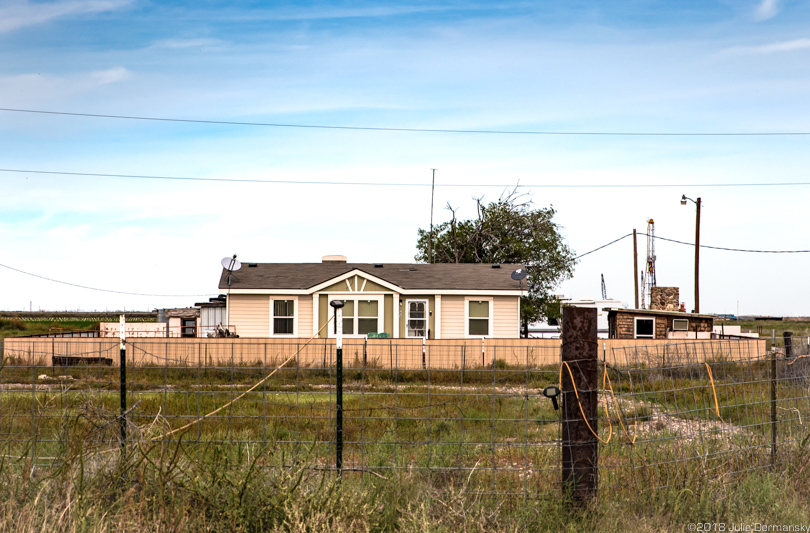 Franklins' home in West Texas with a drilling rig behind it