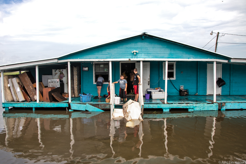A family inspect a flooded home on Isle de Jean Charles