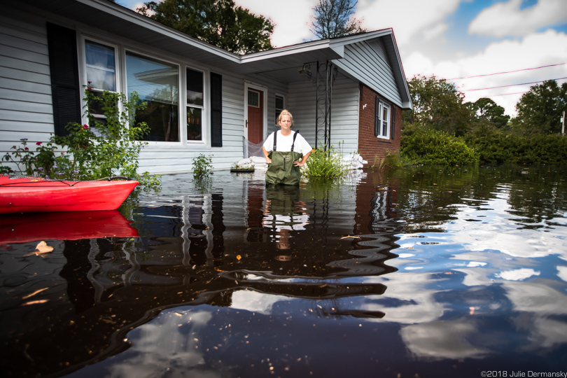 April O'Leary stands in chest waders in floodwaters outside her home in Conway, South Carolina