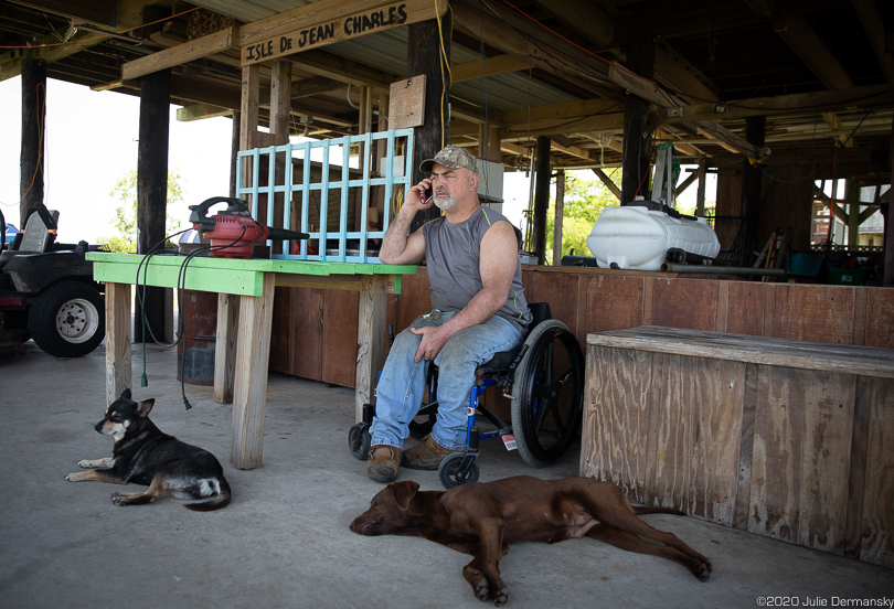 Chris Burnet with his dogs under his Isle de Jean Charles home