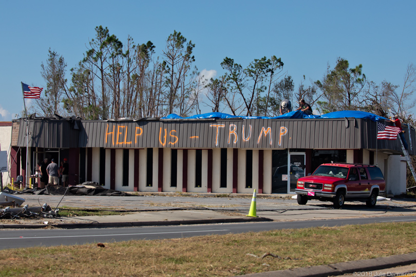 Building damaged by Hurricane Michael with a message asking Trump for help