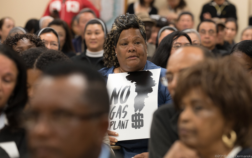 Sylvia McKenzie holds a 'no gas plant' sign on a Louisiana Department of Environmental Quality air permit hearing