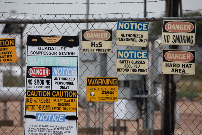 Warning signs on a fracking industry site fence in the Permian Basin