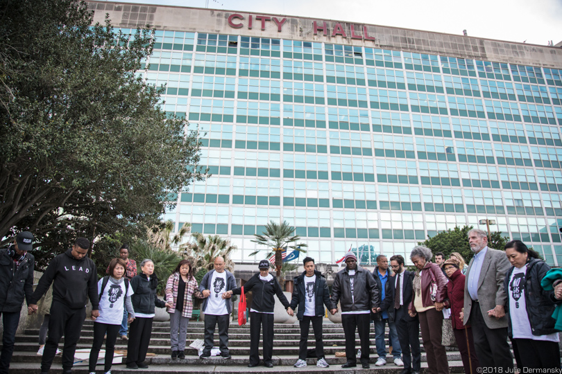 A gathering of those opposed to the Entergy gas plant hold hands outside City Hall after the council vote