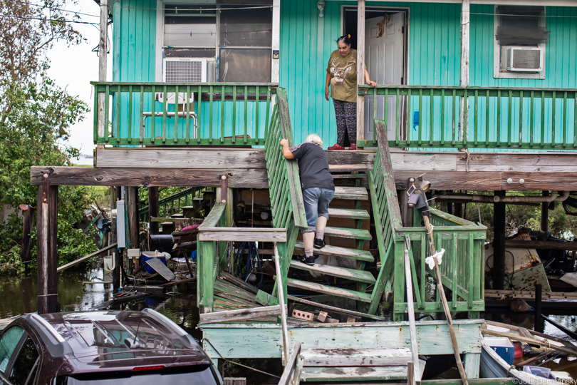 Edison Dardar climbing broken stairs to his home amid floodwaters 