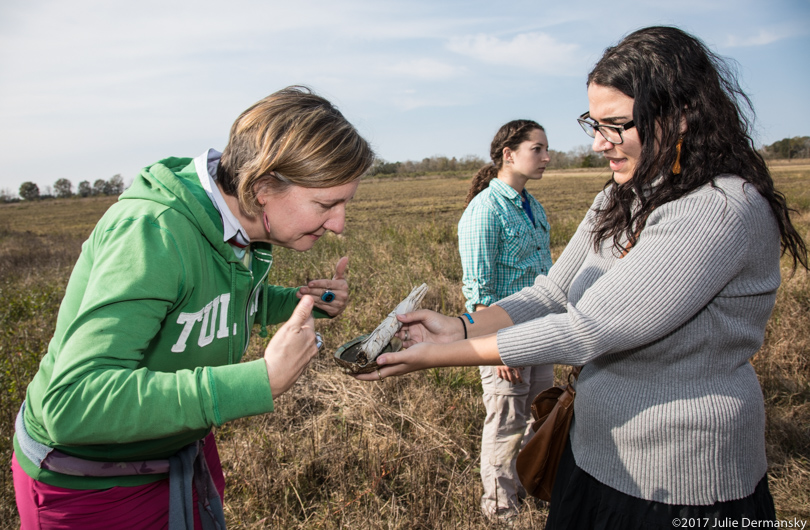 Anne Rolfes leans over a woman holding out burned sage