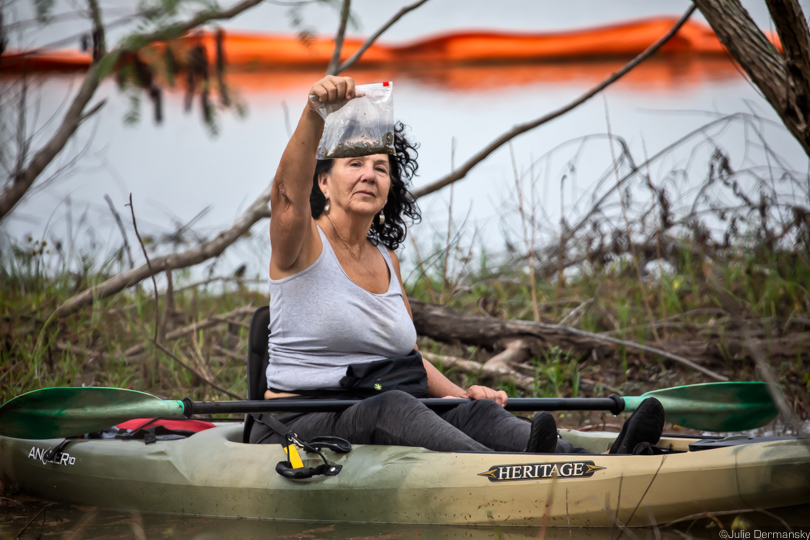 Diane Wilson holds a bag of nurdles over her kayak after collecting them from Formosa's outfall