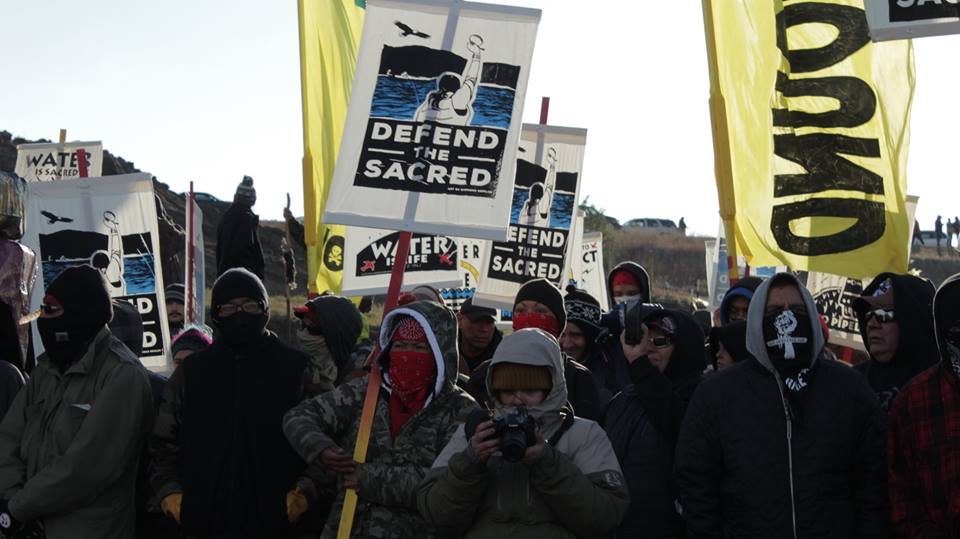 Pipeline protesters holding signs calling to 'Defend the sacred.'