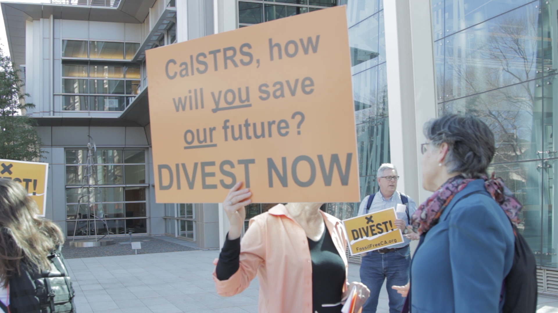 Protester with sign about CAlSTRS divesting from fossil fuels