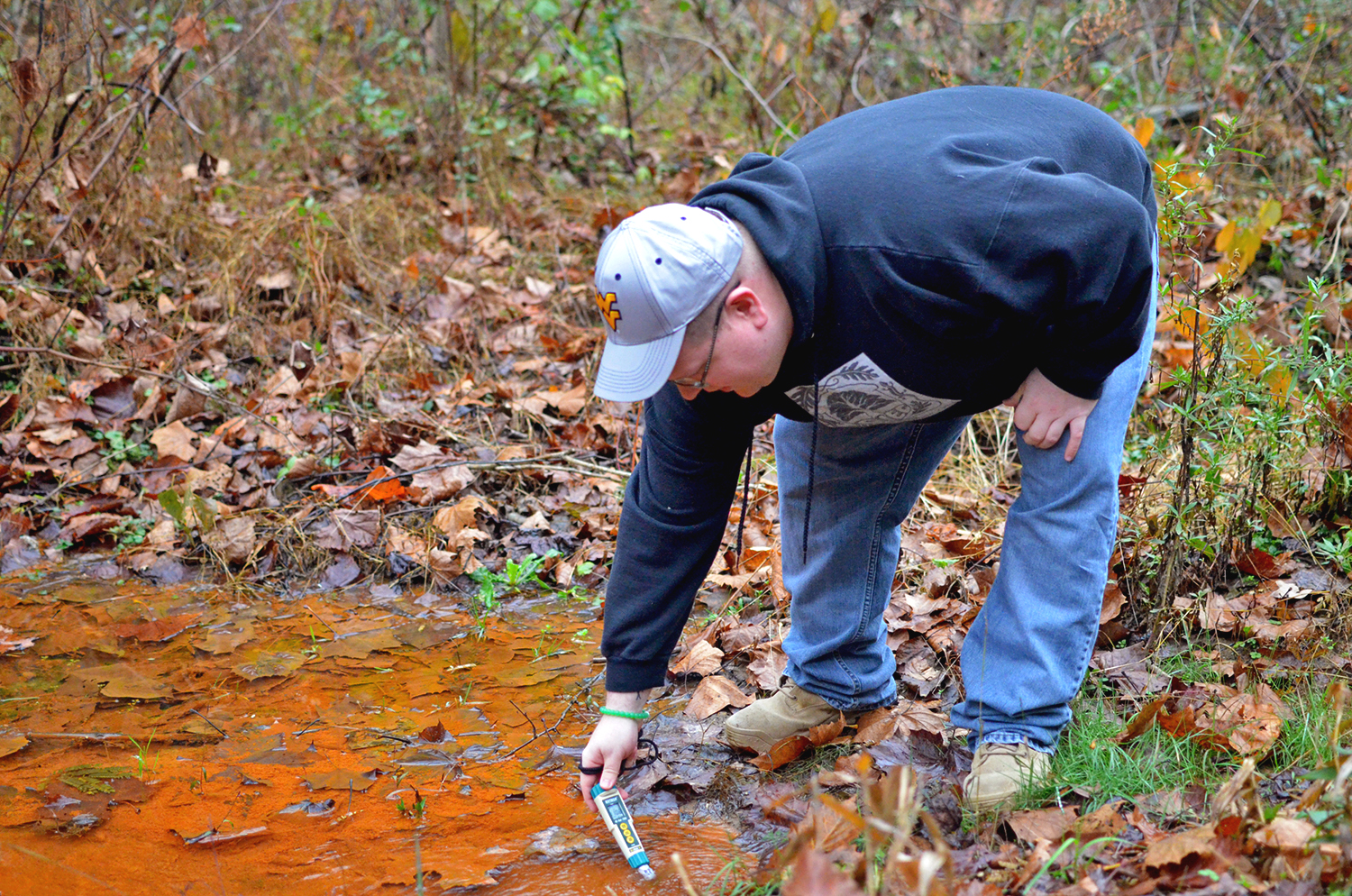 Dustin White of the Ohio Valley Environmental Coalition tests the quality of water in a stream that’s tainted orange from acid mine drainage in southern West Virginia.