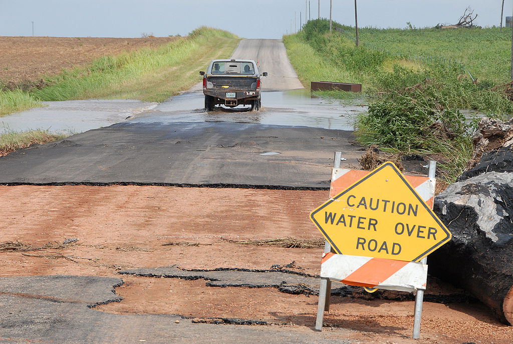 Truck driving past "caution water over road" sign in Oklahoma