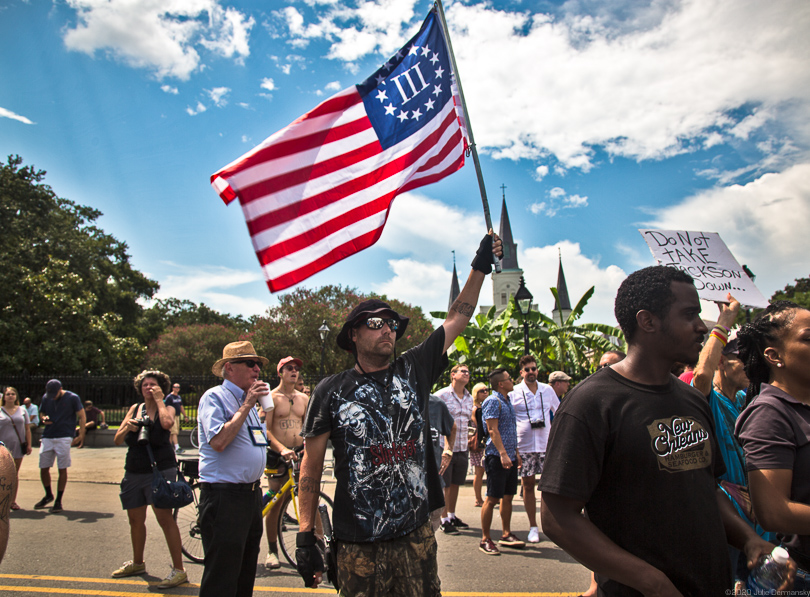 Protester at a confederate memorial in Louisiana waves a Three Percenter flag