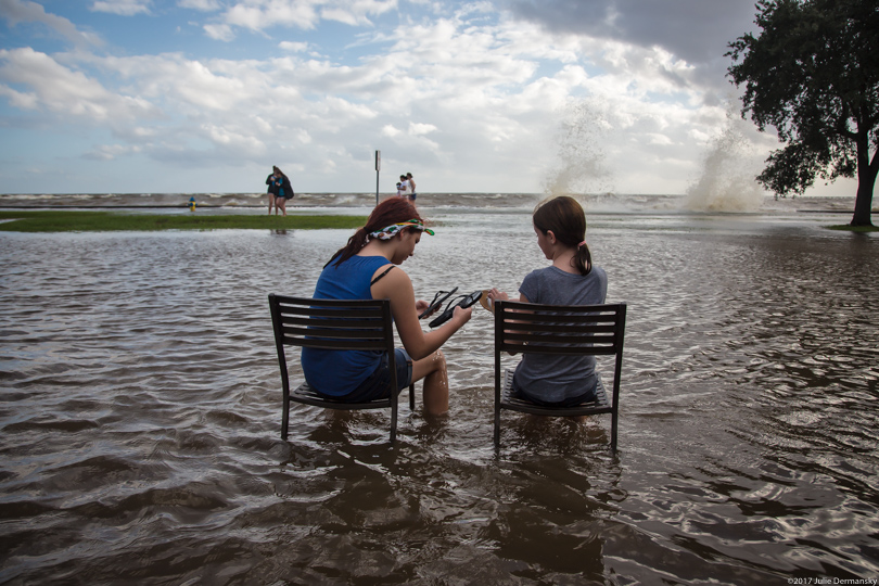 Two girls sit in chairs on the flooded lakefront of Louisiana's Lake Pontchartrain in August 2017.
