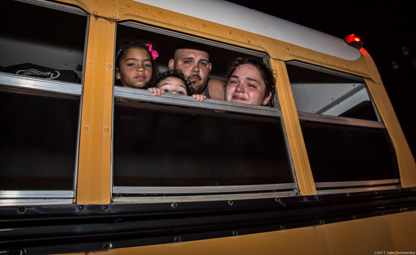 A family of four peak out the window of a bus sent to evacuate them from Hurricane Harvey's flooding in Vidor, Texas