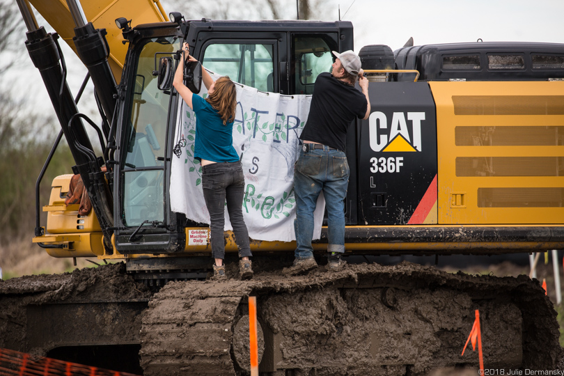 Activists hang a sign on Bayou Bridge pipeline construction equipment to stop work