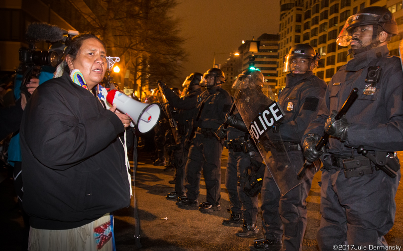 A Standing Rock supporter holds a megaphone next to riot police