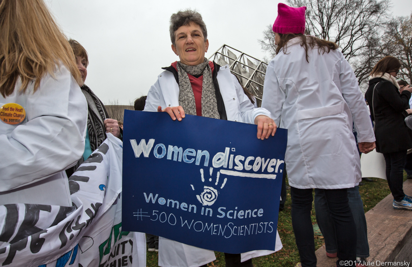 Climate scientist Dominique Bacheler holds a sign that says "Women discover."