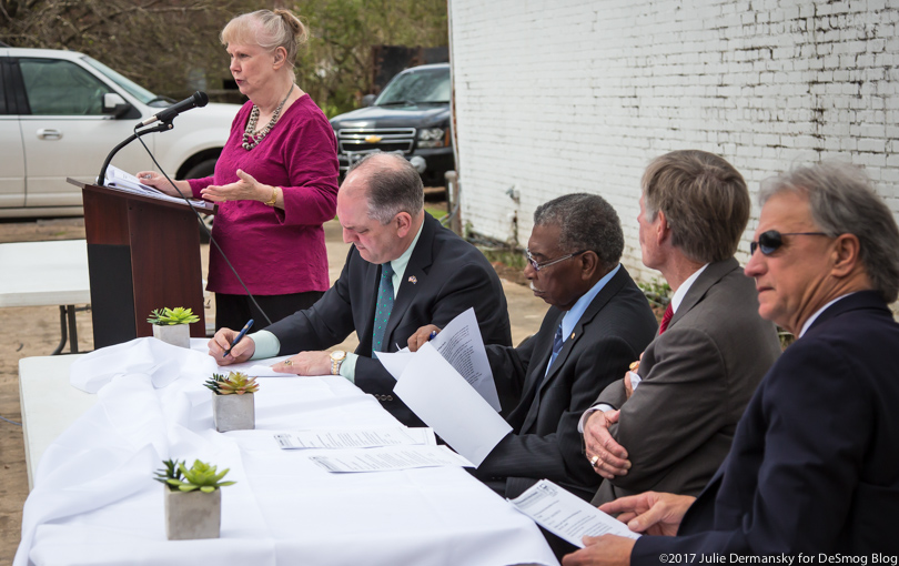 Wilma Subra speaks at a podium next to a panel of other speakers, including Governor John Bell Edwards