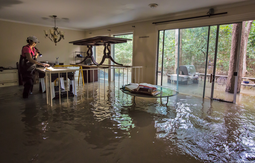 A woman examines her flooded living room in Houston after Hurricane Harvey