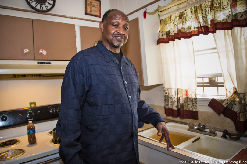 Roy Bowman next to his kitchen sink filled with dirty water.