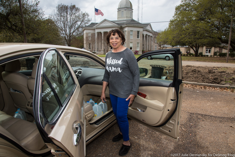 Mamie Fields, the mayor's wife, loads jugs of clean water into her car.