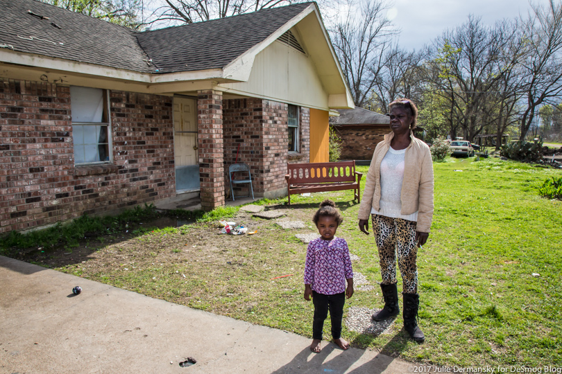 Maxine Washington stands in front of a house with her young granddaughter.