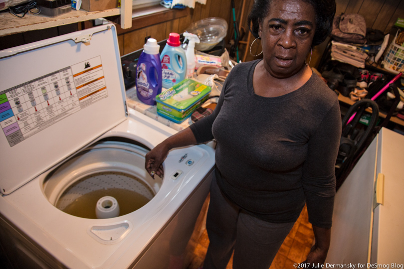 Rudy Shorts next to her washing machine filled with dirty water.