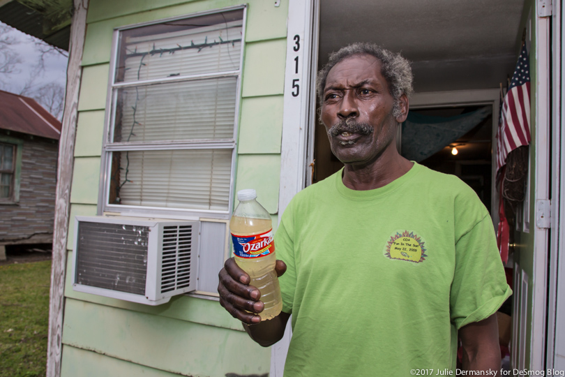 Eddie Sanders holds a bottle of dirty water on his porch.