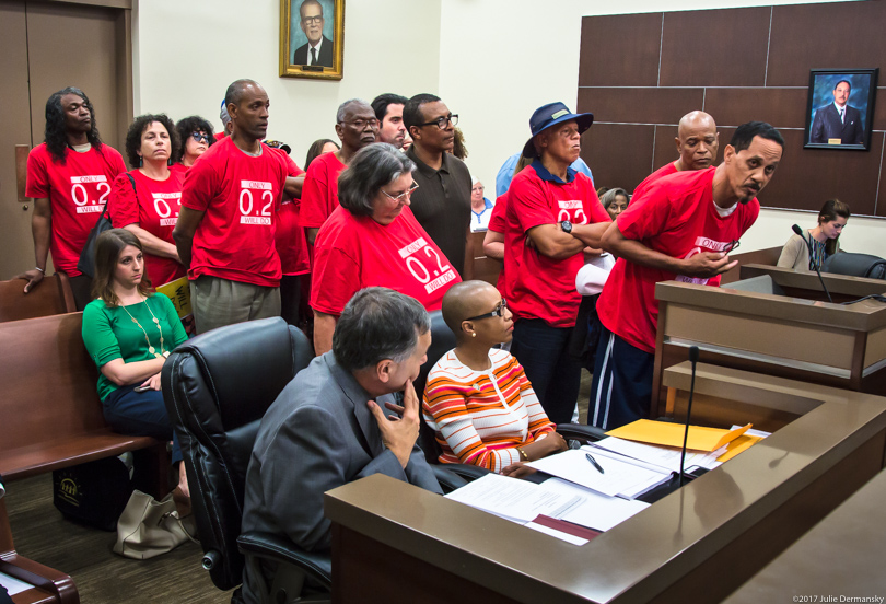 Wearing matching red t-shirts, the members of Concerned Citizens of St. John line up at a parish council meeting
