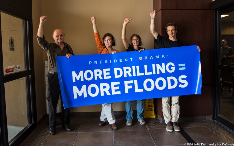 Protesters hold a sign to President Obama saying 'More drilling = more flooding'