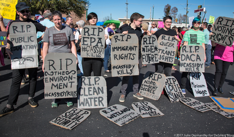 Protesters holding signs in the shape of tombstones stand outside Sen. Cassidy's town hall meeting