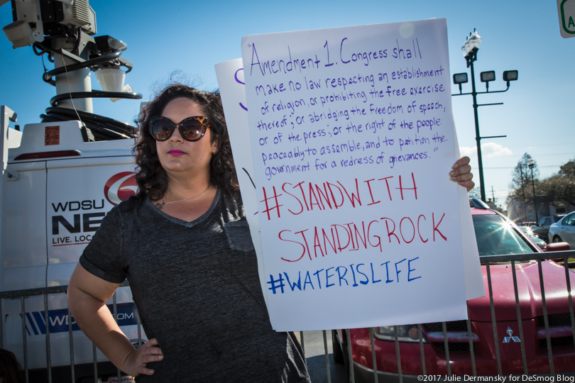 A protester outside Sen. Cassidy's town hall holds a sign with the First Amendment written on it.