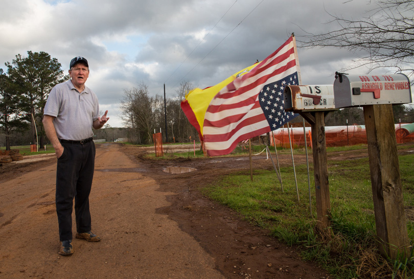 Landowner Michael Bishop stands on his property next to an upside-down American flag