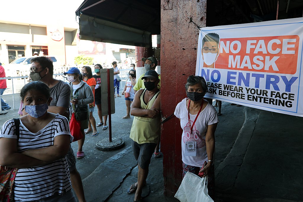People in face masks in line to enter a market in Angono, Philippines