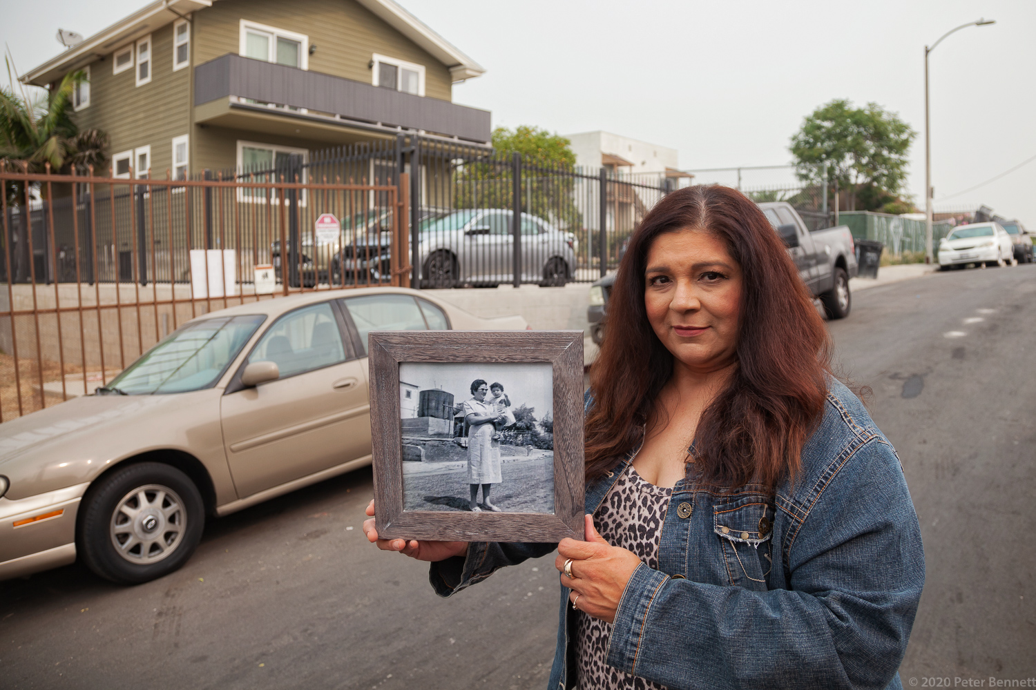 Lifelong resident and neighborhood activist Rosalinda Morales stands on Firmin Street in the same location as a photo from 1958 of her aunt holding her in front of an oil tank. Dozens of abandoned wells still lie under homes and below ground along Firmin Street.