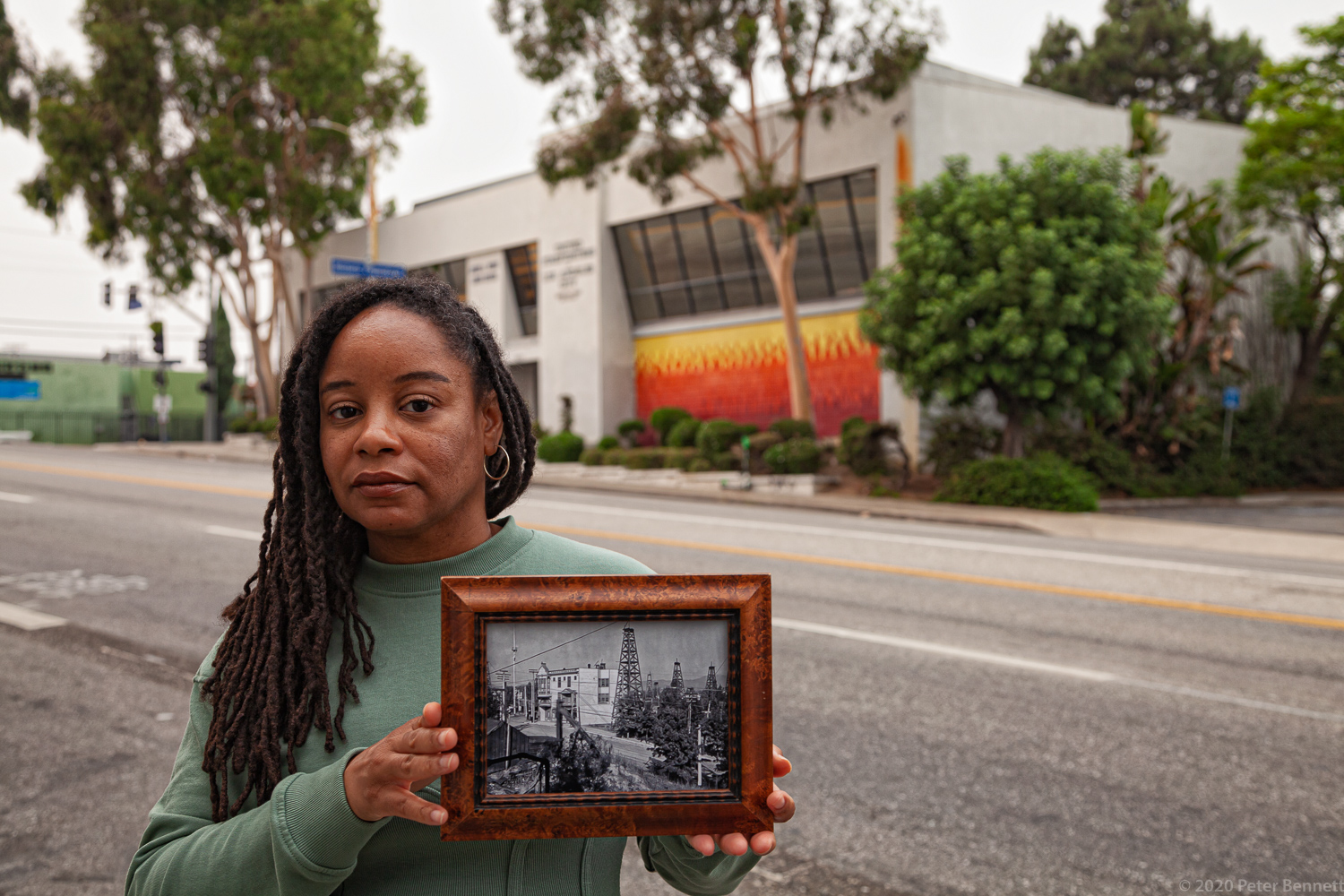 Resident Mercedes Yolanda Cooper holds a 1905 photo of the intersection of W. 1st Street and Belmont Ave in Los Angeles