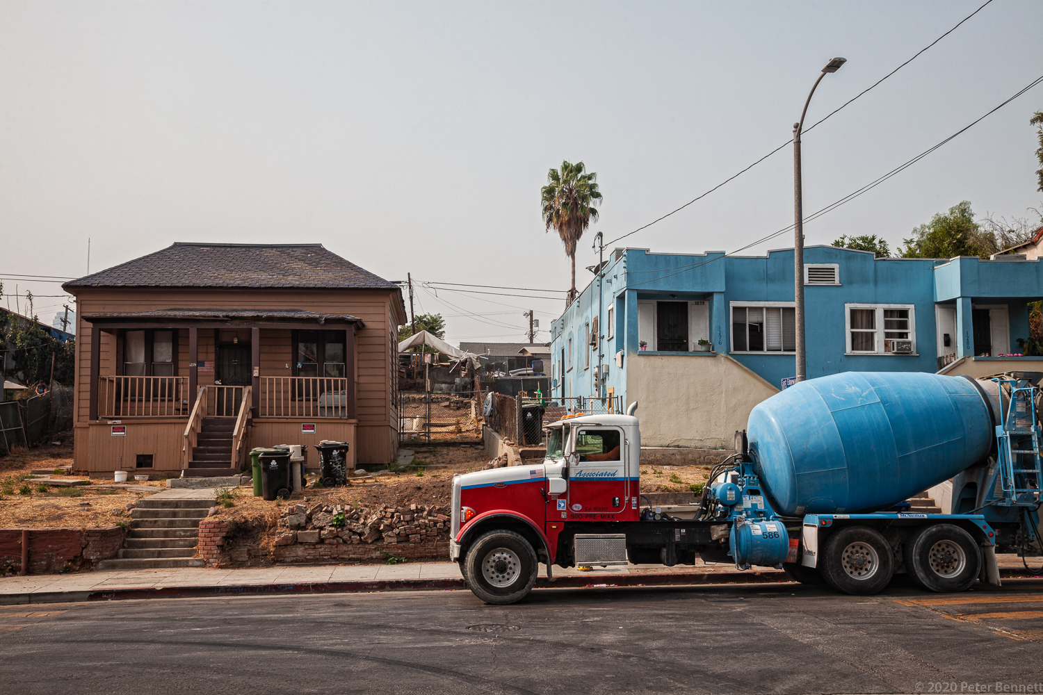 Cement mixer trucks line up in front of a home once surrounded by oil wells, to deliver their load to a construction site on Court Street.
