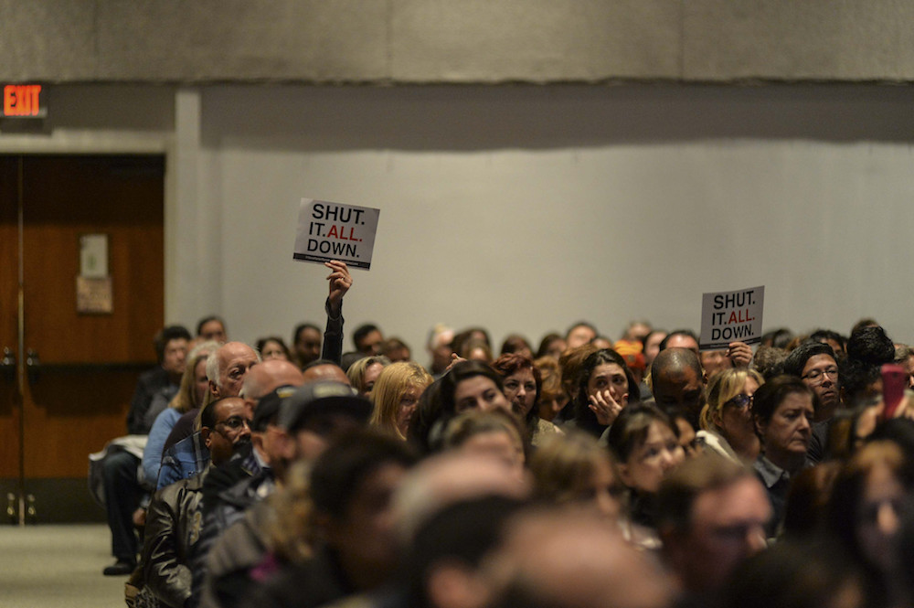 People hold signs calling to shut down Aliso Canyon at a community briefing in 2016