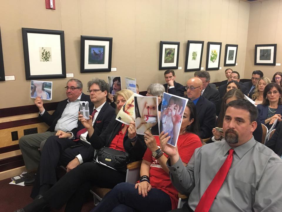 People sitting at the SB57 hearing hold photos of physical ailments they attribute to gas leaks from Aliso Canyon