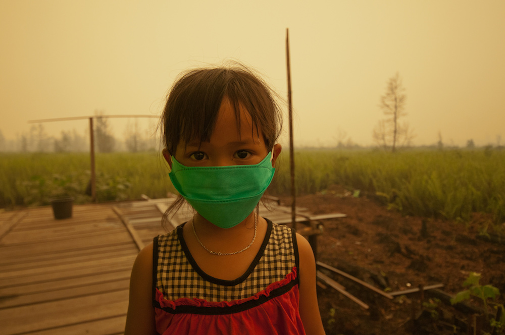 Child with mask from toxic smoke from peat land fires in Indonesia.